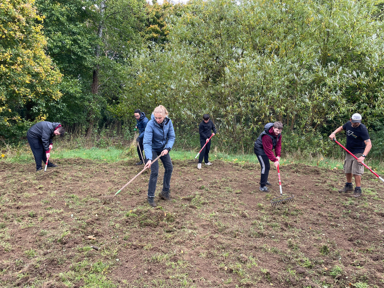 Bartholomew students raking Eynsham Primary School's meadow before seeding